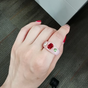 Close-up of a pink resin ring with colorful rectangular red gem and rhinestone accents