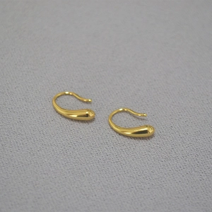 Nahaufnahme eleganter goldener Wassertropfen-Ohrringe mit polierter Spiegeloberfläche
