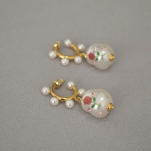 Detailed macro of baroque pearl earrings with rose pattern and small pink crystals