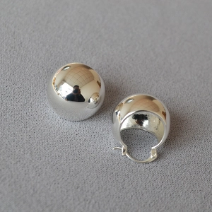 Detailed view of chunky silver-colored brass hoop earrings with high-polish mirror finish