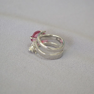 Dettaglio macro di anello d'argento a doppio strato con cuore rosa e ciondolo a fiore