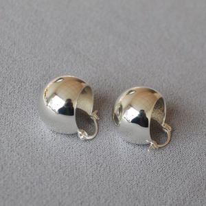 Detailed view of glossy silver hollow ball earrings with a mirror polished finish