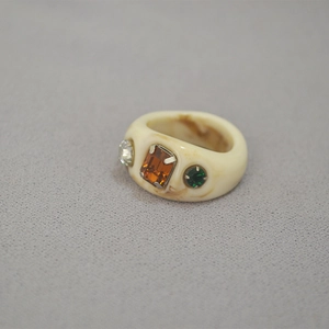 Detail view of cream resin ring with marble texture and three colorful inlaid gemstones