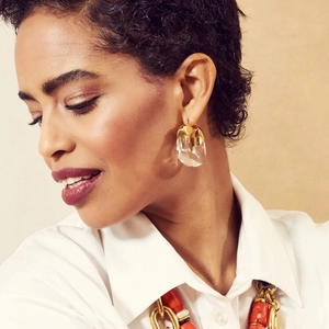 U-shaped gold-plated resin earrings and red beaded chain necklace on a female model