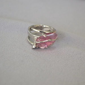 Dettaglio anello argento con cristallo rosa su tessuto grigio testurizzato