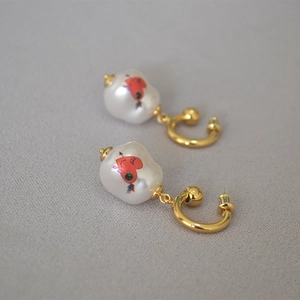 Detailed view of Baroque pearl earrings with heart painting and gold-plated finish
