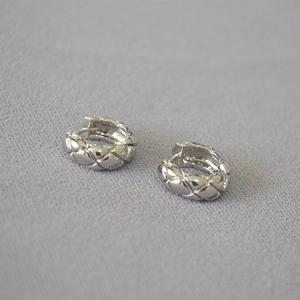 Detail shot of silver quilted pattern on minimalist geometric hoop earrings
