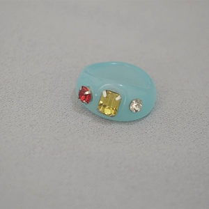 Detailed macro view of light blue resin ring featuring embedded colorful rhinestones