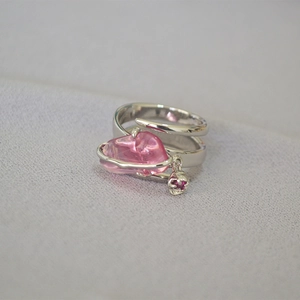 Dettaglio anello argento con cristallo rosa e piccolo ciondolo a forma di fiore