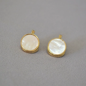 Vue détaillée de boucles d'oreilles rondes dorées avec incrustation de nacre irisée