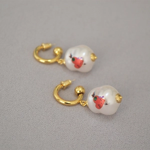 Detailed macro of baroque pearl drop earrings with colorful heart and arrow art print