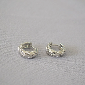 Macro shot of silver quilted pattern hoop earrings with minimalist polished finish