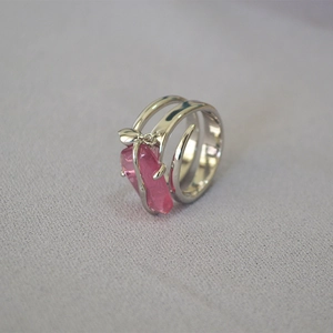 Dettaglio macro di un anello d'argento con un cristallo rosa grezzo dal design a fascia