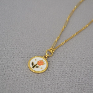 Detailed macro of vintage brass gold tulip pendant necklace on grey knit texture