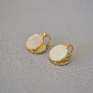 Gros plan de boucles d'oreilles dorées avec nacre rose irisée et design minimaliste