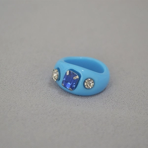 Close-up of sky blue resin ring with rectangle blue gemstone and clear zircon accents