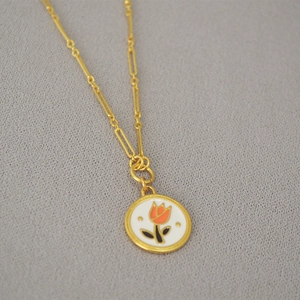 Retro brass gold-plated necklace with a white enamel tulip flower pendant on gray fabric
