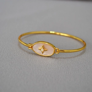 Détail d'un bracelet doré avec nacre rose et incrustation d'opale en forme d'étoile