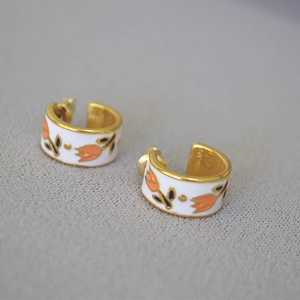 Detailed macro shot of vintage brass gold earrings with orange tulip enamel floral patterns