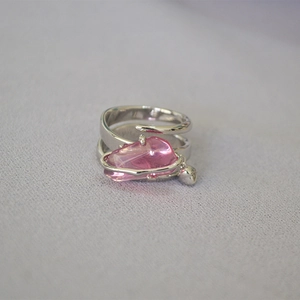 Dettaglio di un anello d'argento con cristallo rosa irregolare su tessuto color lilla