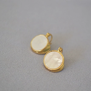 Détail d'incrustation de nacre ronde sur des boucles d'oreilles dorées élégantes