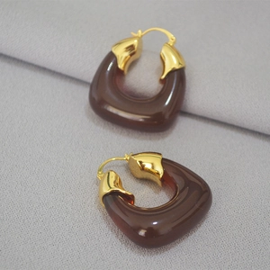 U-shaped amber resin earrings with gold-plated metal clips on grey textured background