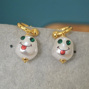 Detail of French vintage baroque pearl drop earrings with quirky green eye print