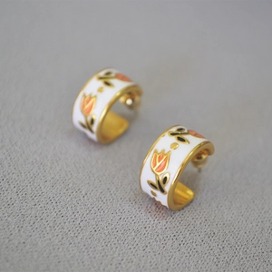 Close-up of vintage brass tulip earrings with white enamel and hand-painted flowers