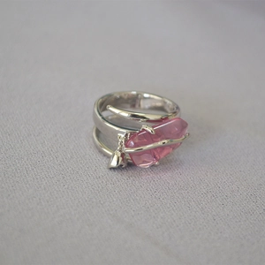 Dettaglio anello argento a spirale con cristallo rosa irregolare e piccolo ciondolo