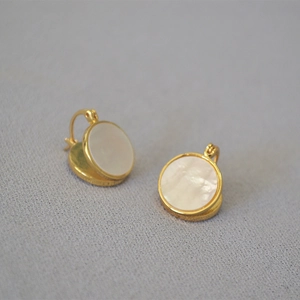 Détail de boucles d'oreilles en laiton doré avec incrustation ronde en nacre blanche