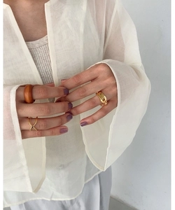 Detail shot of gold chain ring and wooden band worn with sheer white blouse