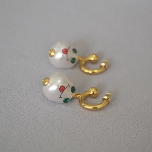 Close-up of French vintage baroque pearl earrings with golden cartoon face and red tongue