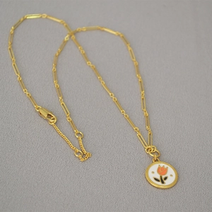 Detail of gold-plated tulip enamel coin pendant on a stylish paperclip link chain