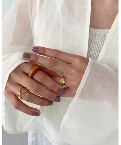 Detailed view of layered gold chain rings and textured bands on a model's hand