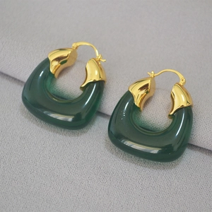 Detail of dark green translucent resin U-shape earrings with gold-plated metal clasp