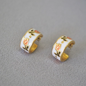 Detail of vintage brass tulip earrings with white enamel and hand-painted floral patterns