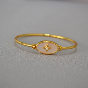 Vue détaillée du bracelet en laiton doré avec incrustation rose ovale et étoile centrale