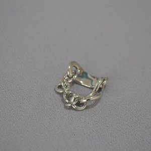 Detail of silver chain link ring with hammered texture on a textured grey background