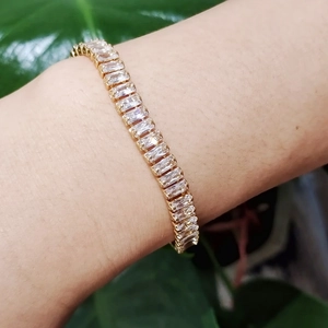 Bracelet élégant en or avec zircons brillants de taille rectangulaire porté au poignet