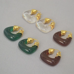 Detail of U-shaped resin earrings in clear, emerald, and amber with gold-plated accents