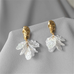 Macro shot of elegant white petal drop earrings with gold textured metal hooks and pearly veins