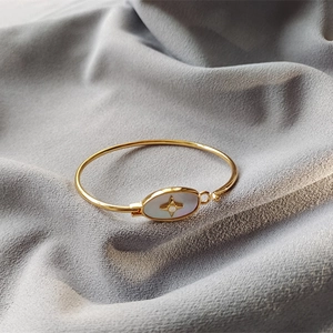 Détail d'un bracelet doré avec un ovale en nacre et une étoile étincelante incrustée