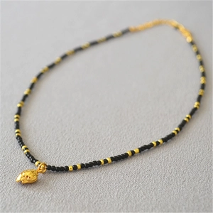 Hawaiian style necklace with black seed beads and a gold-plated shell pendant decoration