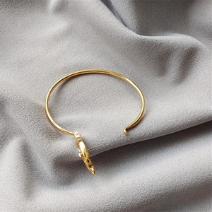 Gros plan d'un bracelet en laiton doré avec texture matelassée et incrustation en nacre