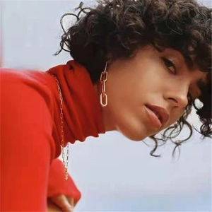 Close-up of elegant gold chain earrings and necklace worn on a red sweater background