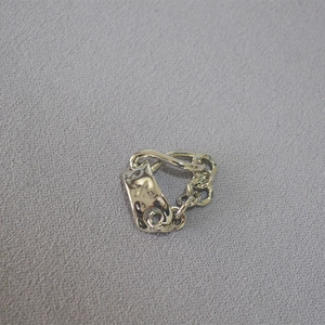 Macro shot of silver textured irregular chain ring with hammer finish on gray fabric