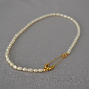 Macro shot of freshwater rice pearls with creative gold safety pin buckle detail
