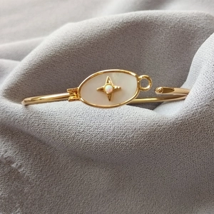 Détail du bracelet doré avec incrustation de nacre et breloque étoile en opale