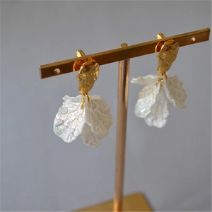 Golden irregular metal stud earrings with iridescent white pleated petal dangles