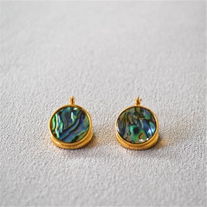 Vue macro de boucles d'oreilles en laiton doré avec incrustations d'abalone irisées colorées